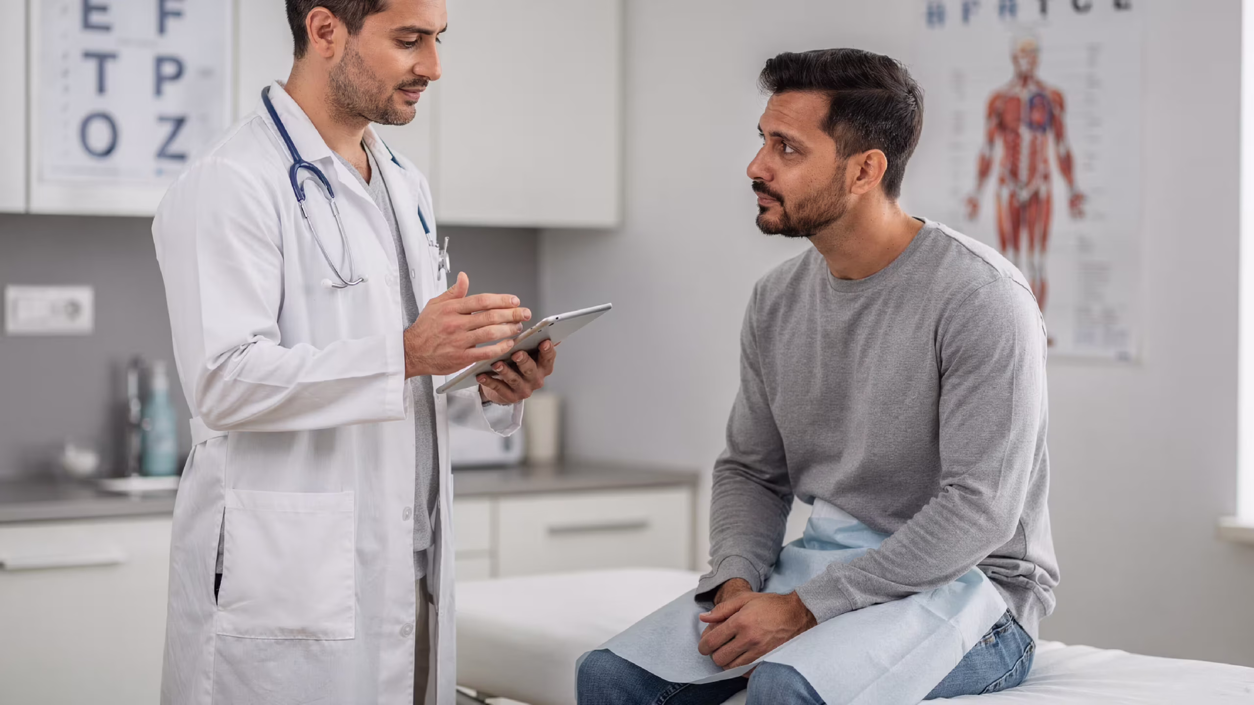 A doctor using a tablet in front of a patient with a Goodx dashboard Physician accessing electronic health records on a tablet during patient consultation